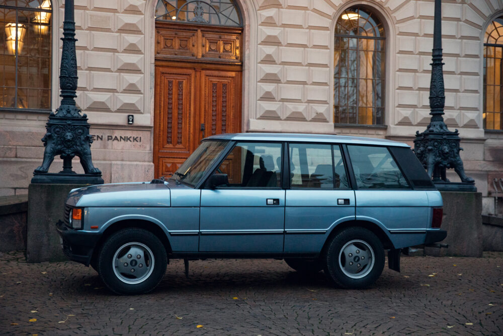 Vintage blue SUV parked beside historic building entrance