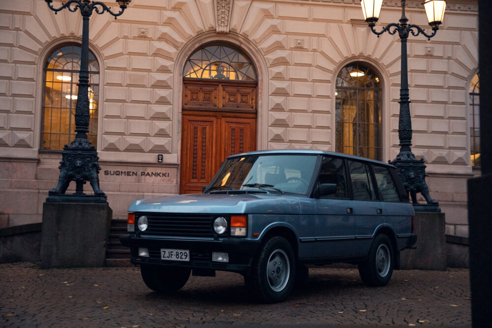 Vintage car parked outside Suomen Pankki building at dusk