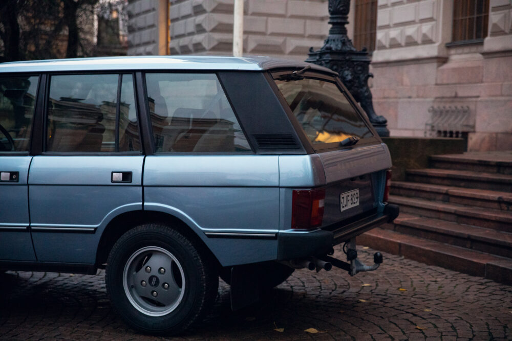 Vintage station wagon parked near city building steps.
