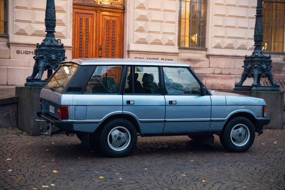Vintage blue SUV parked near ornate lamps and building