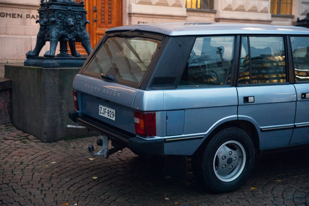 Vintage Range Rover parked near ornate lion statue