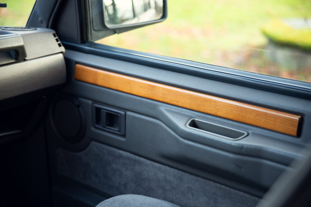 Vintage car door interior with wooden trim and speaker