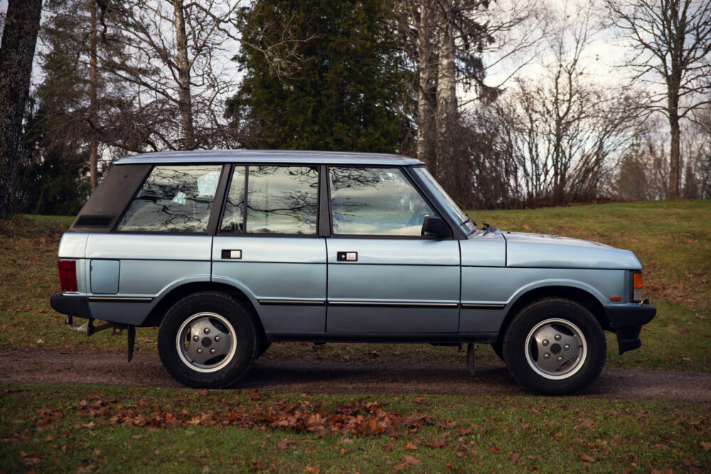 Vintage blue SUV parked in leafy outdoor setting