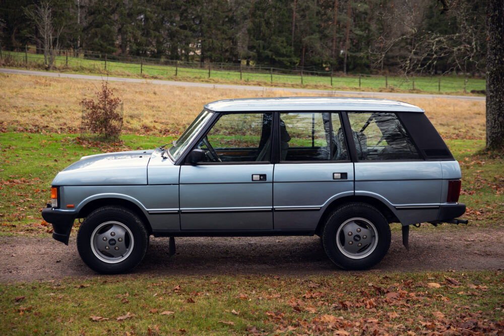 Vintage blue SUV parked in a green grassy field