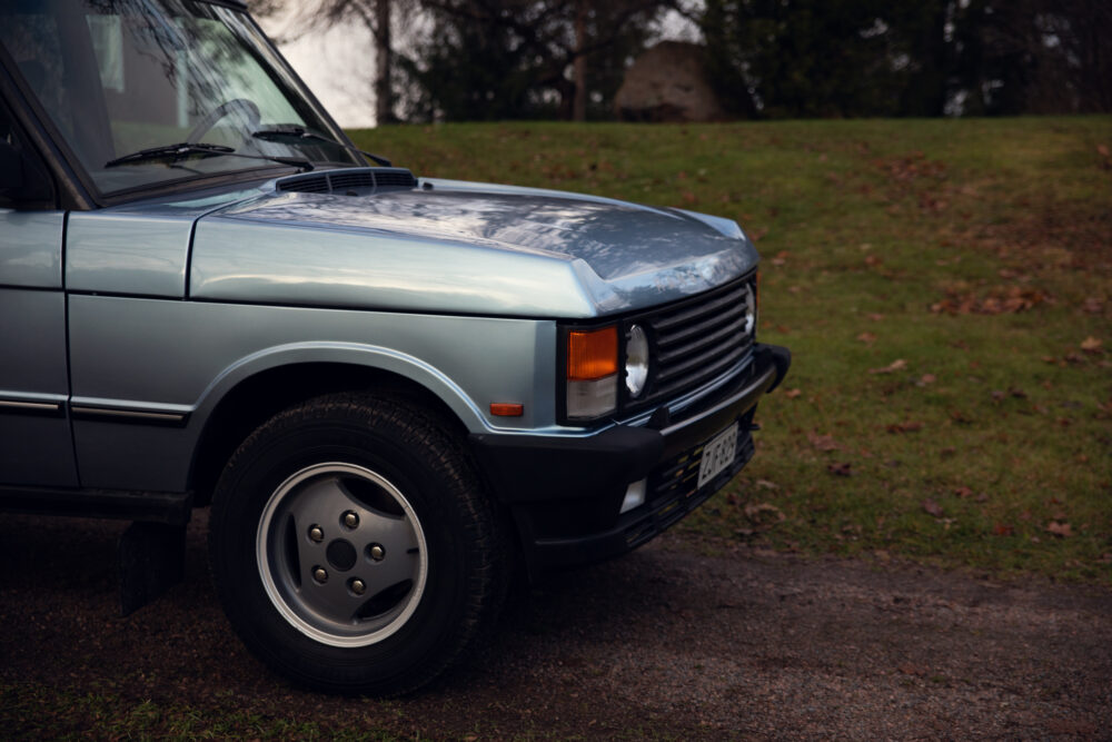 Vintage blue SUV parked on a grassy field