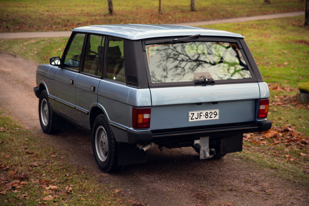 Vintage blue Range Rover parked on leafy path