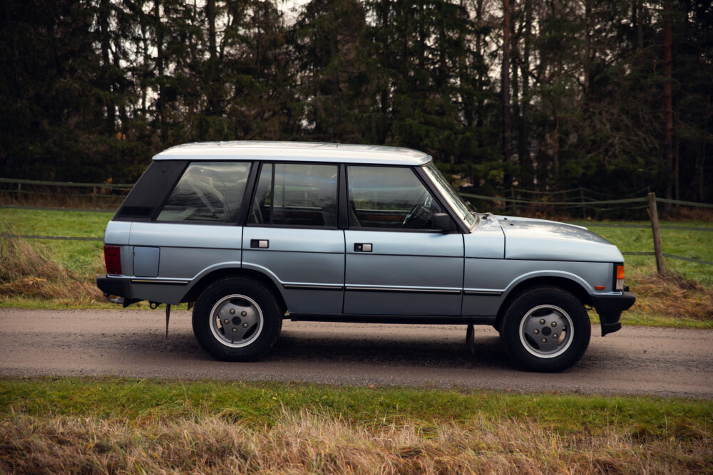 Vintage blue SUV parked outdoors near forest