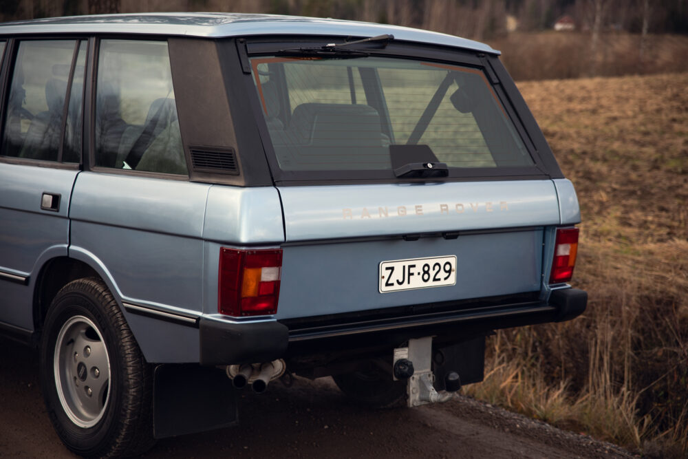 Rear view of classic blue Range Rover on rural road