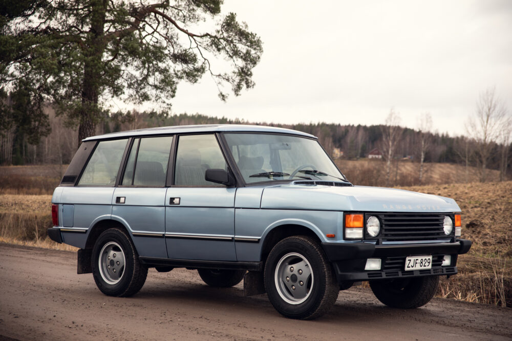 Vintage blue Range Rover parked outdoors near trees