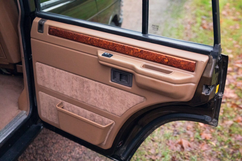 Open car door interior with wood trim and controls