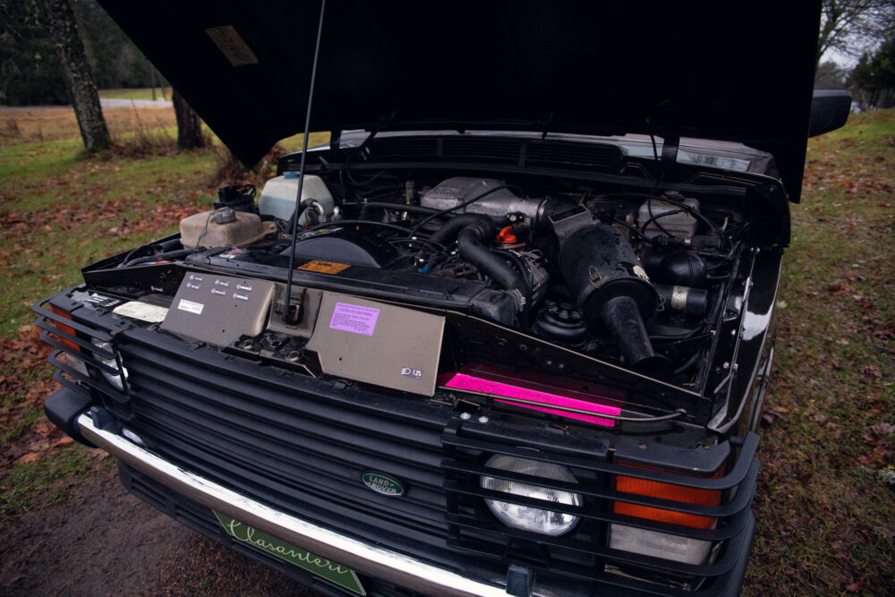 Open hood of a vintage Land Rover showing engine