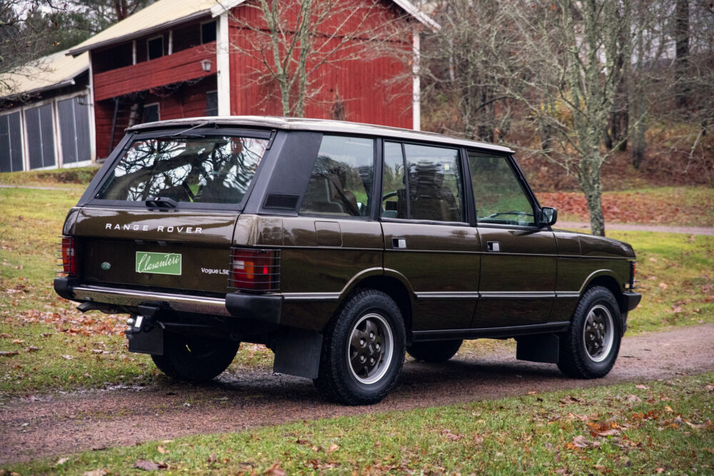 Vintage green Range Rover parked near red barn