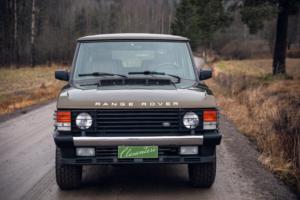 Vintage Range Rover on rural road with autumn trees