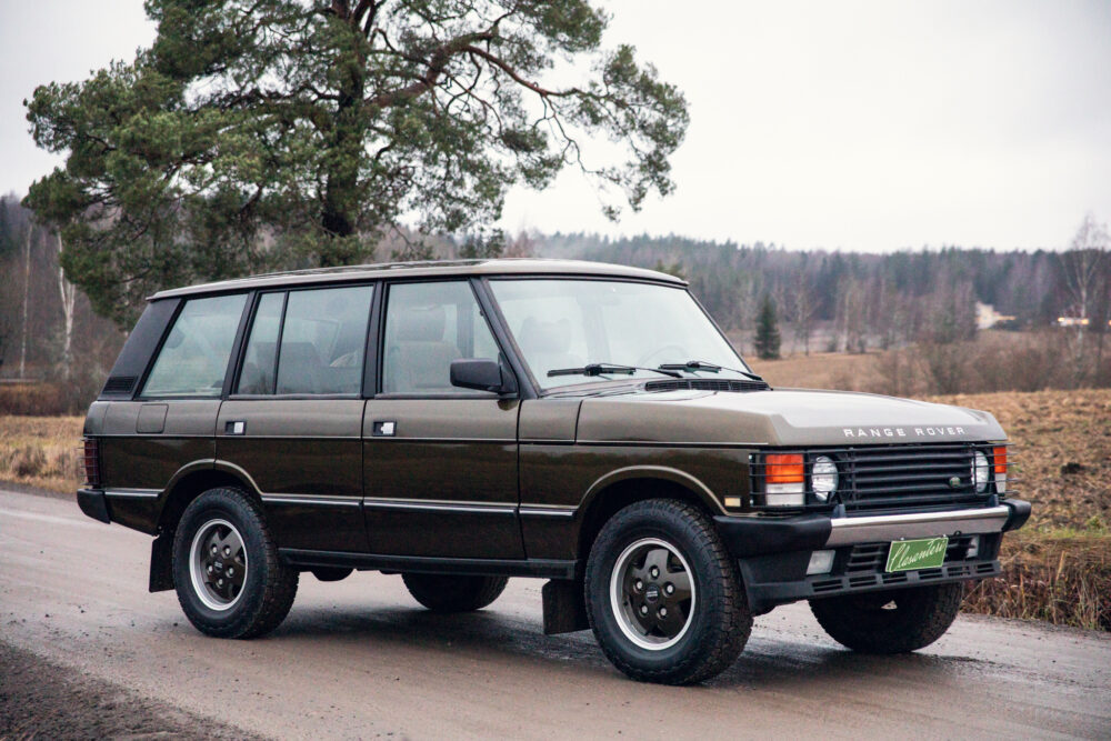 Vintage Range Rover parked beside road near trees