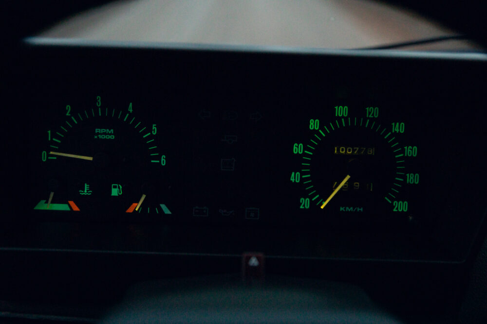 Illuminated car dashboard at night showing speed and RPM