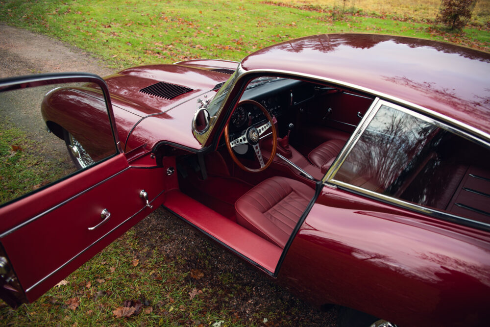 Vintage red car with open door, classic interior design.