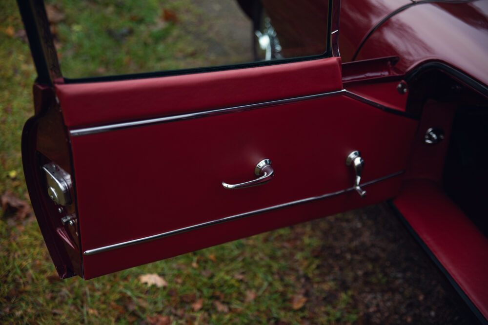 Close-up of classic car's red door and handle