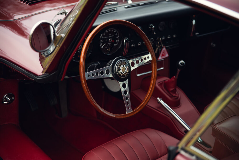 Classic red car interior with wooden steering wheel