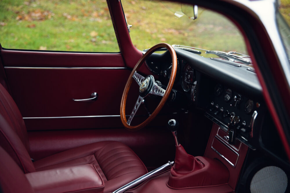 Vintage car interior with red leather and wooden wheel