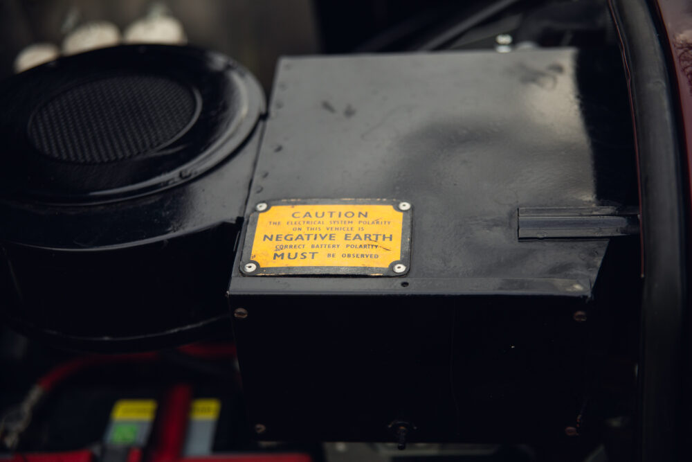 Caution label on vehicle battery indicating negative earth