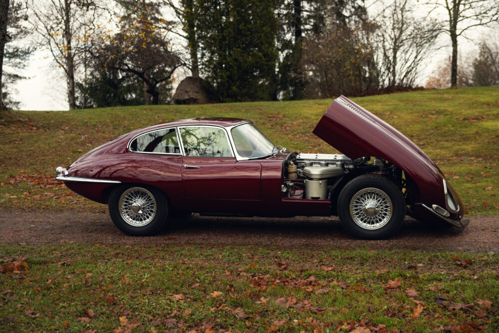 Vintage red car with open hood in autumn park