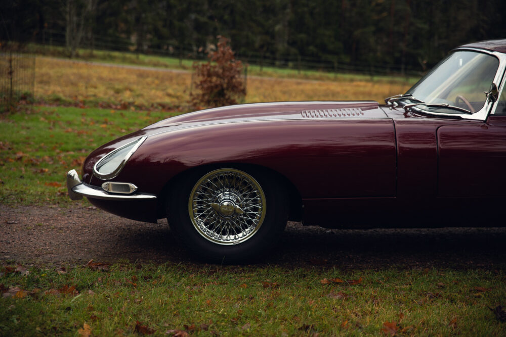 Vintage maroon sports car parked on a grassy field