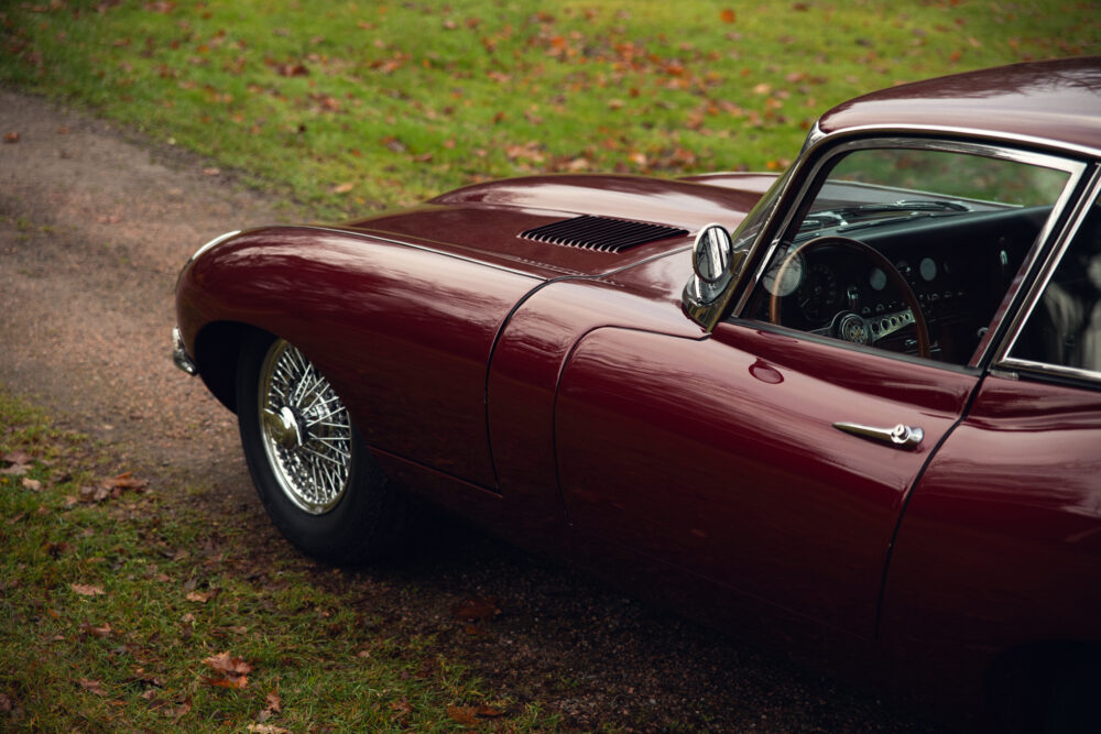 Vintage burgundy car parked on leafy path