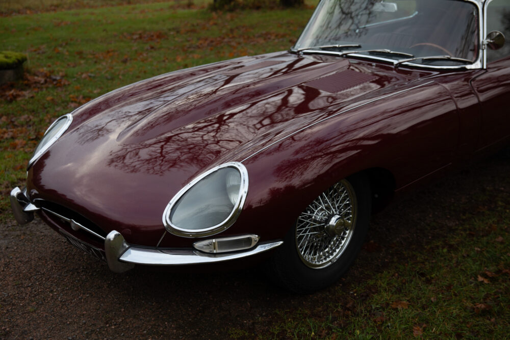 Vintage red Jaguar E-Type car on grassy background