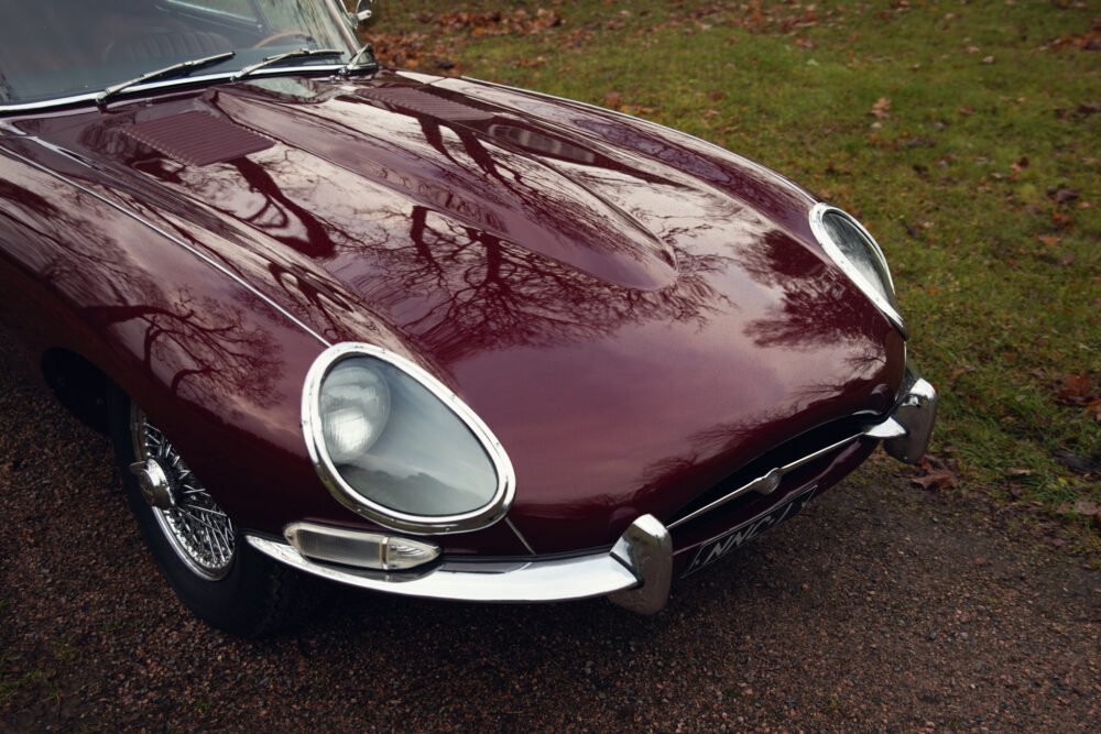 Vintage maroon car parked on leafy roadside