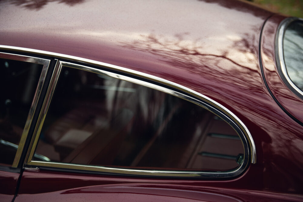 Close-up of vintage burgundy car window and trim