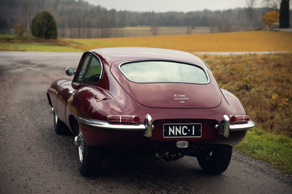 Vintage maroon Jaguar E-Type parked on rural roadside