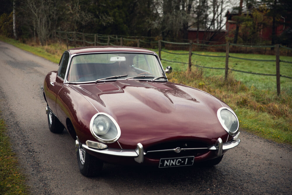 Vintage maroon Jaguar E-Type on rural road