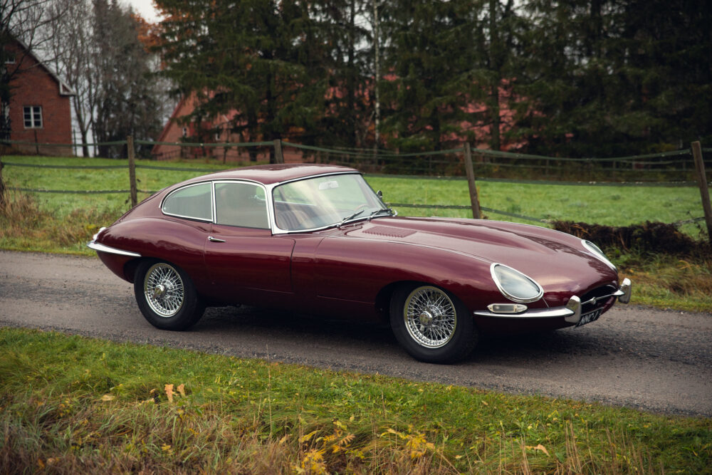 Vintage maroon Jaguar E-Type on rural road