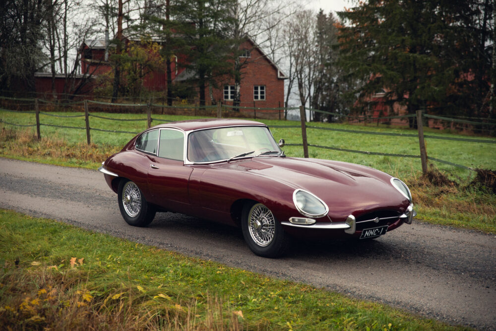 Vintage maroon Jaguar E-Type on countryside road