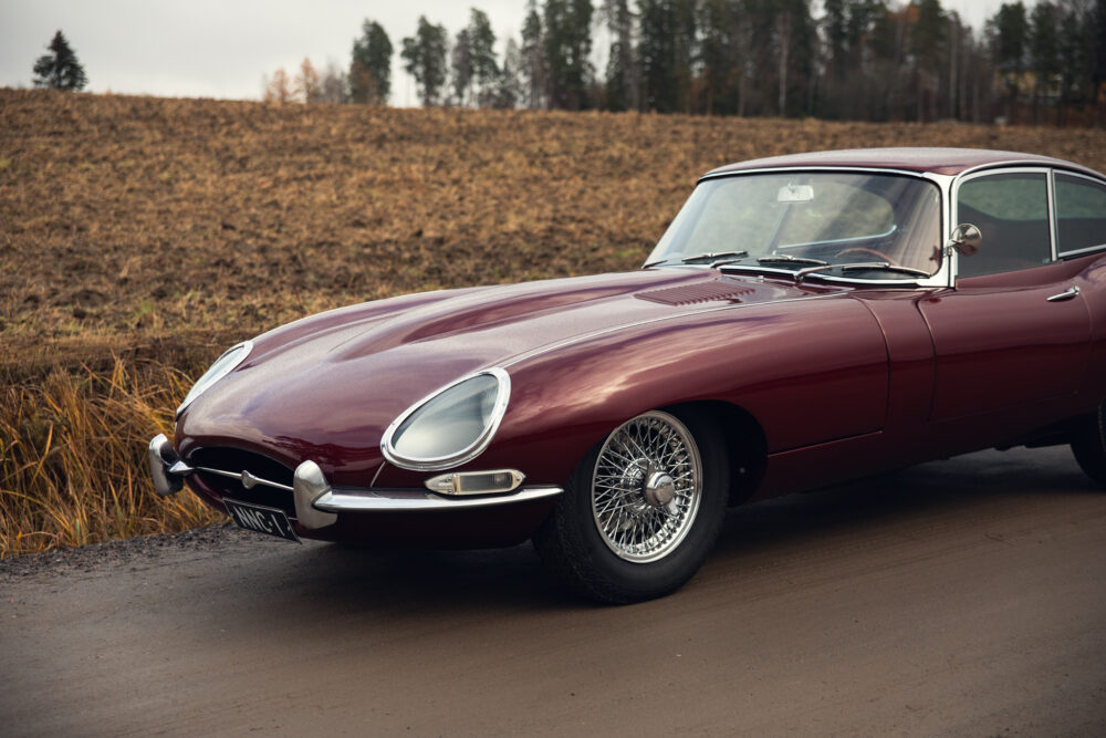 Vintage burgundy Jaguar car on rural road