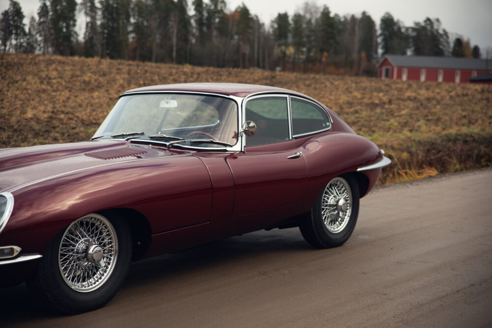 Vintage maroon sports car on rural road near field