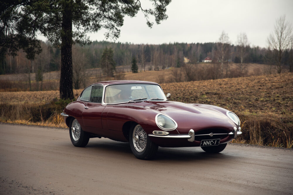 Vintage red sports car parked beside road in countryside