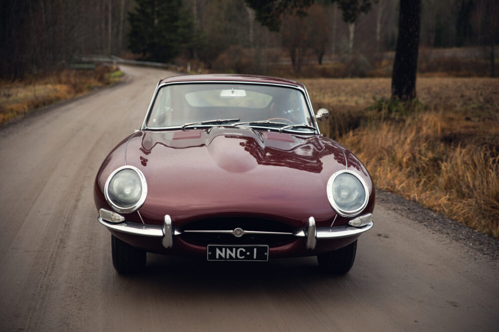 Vintage maroon Jaguar car on rural road
