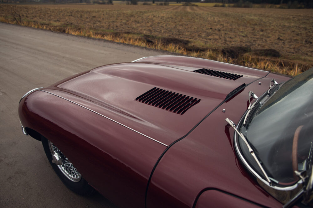 Close-up of vintage burgundy car hood and chrome details