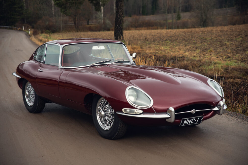 Classic maroon Jaguar E-Type on rural road