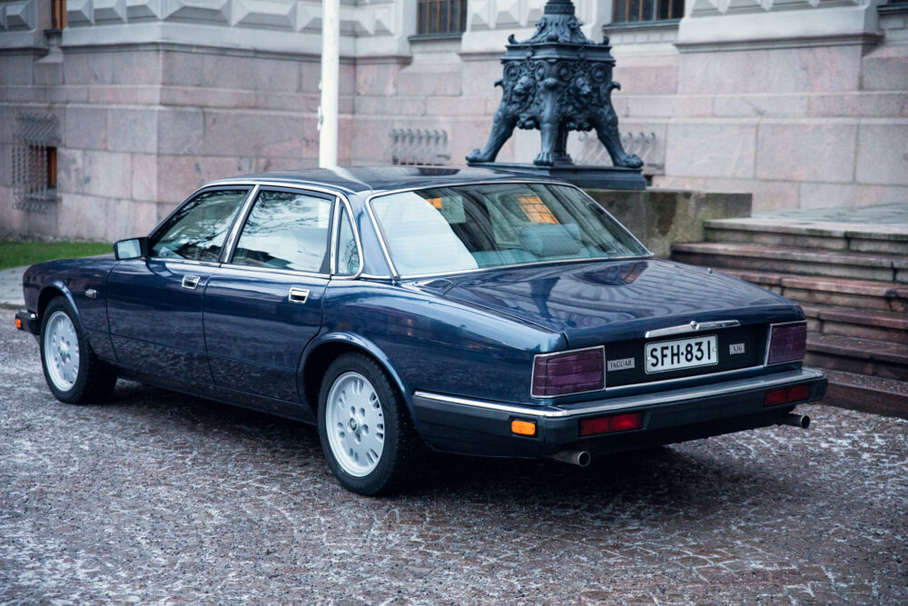 Classic blue Jaguar car parked near ornate statue