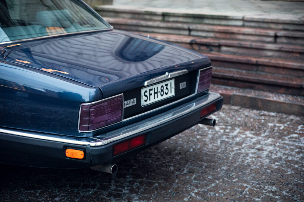 Rear view of blue Jaguar car on cobblestone street