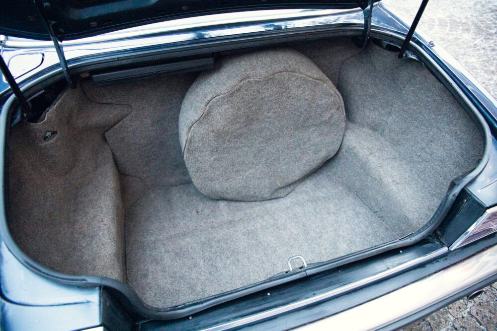 Open car trunk with a large stone inside.