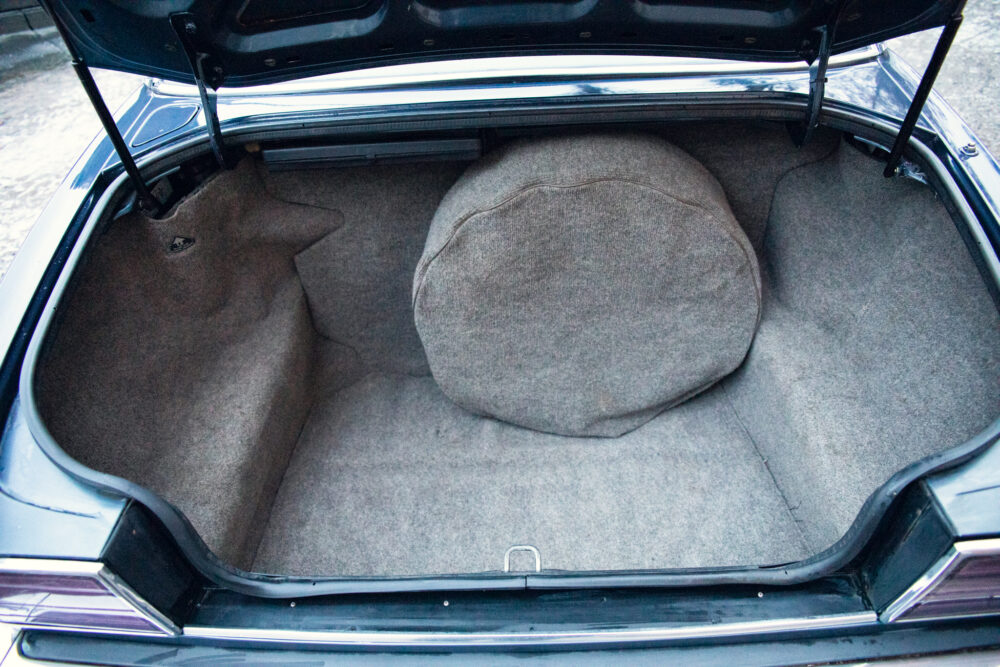 Open car trunk with gray fabric lining and pillow