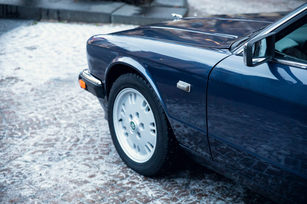 Blue car on snowy cobblestone street at dusk