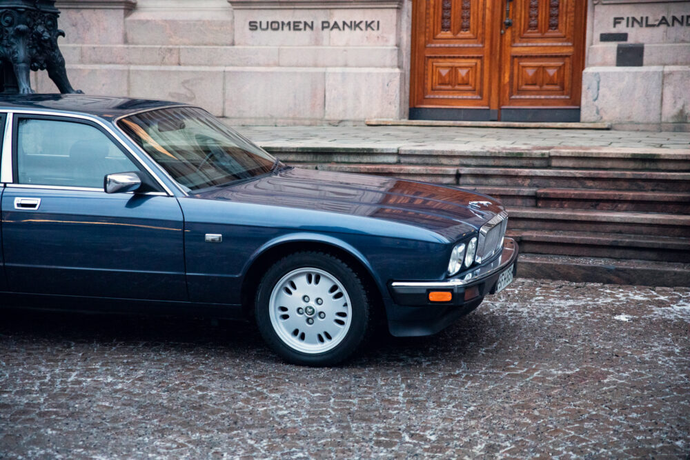 Blue Jaguar car parked in front of Finnish bank