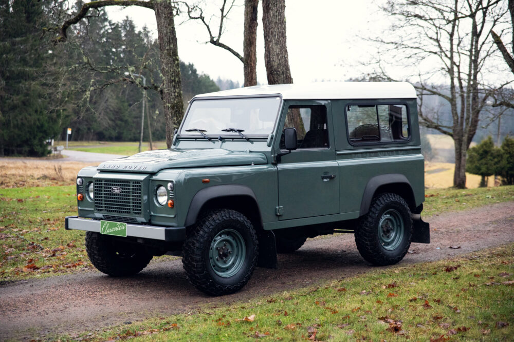 Green Land Rover Defender parked outdoors near trees