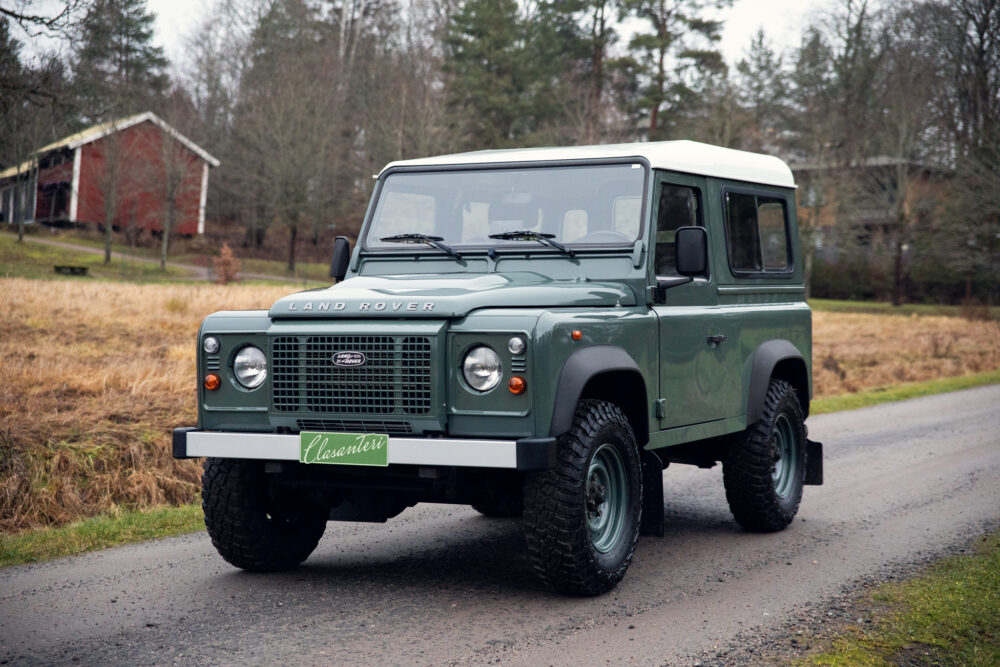 Green Land Rover Defender on rural road