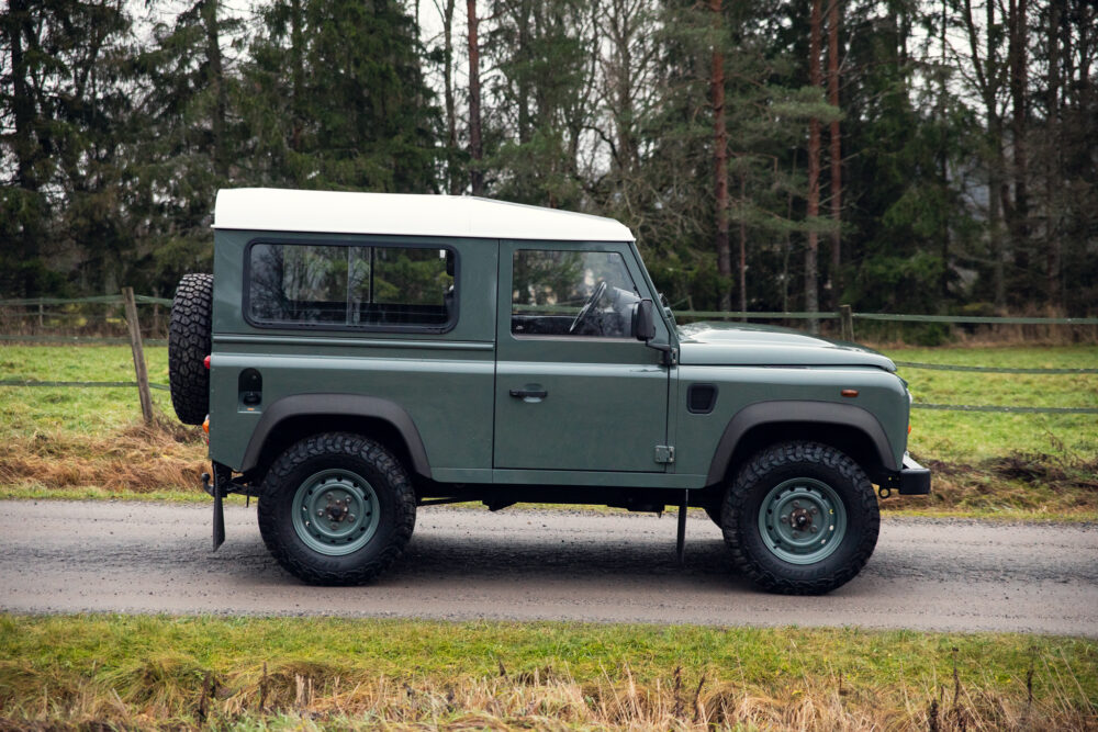 Green SUV parked on rural road near forest