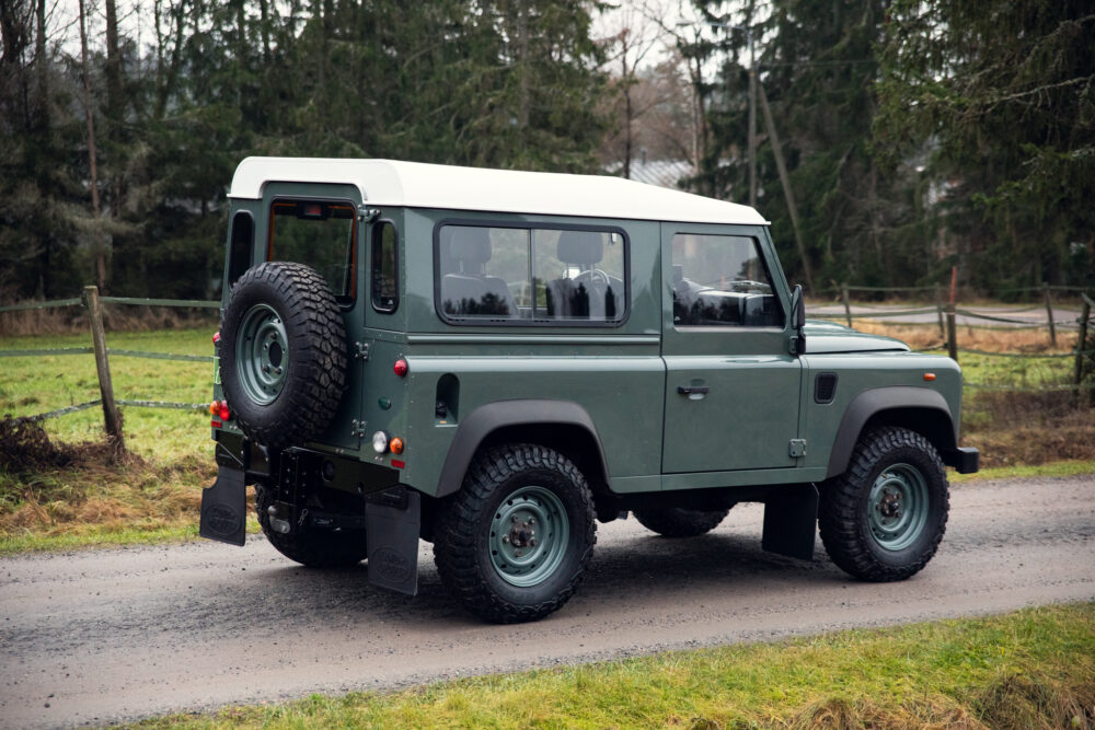 Green Land Rover Defender parked on country road